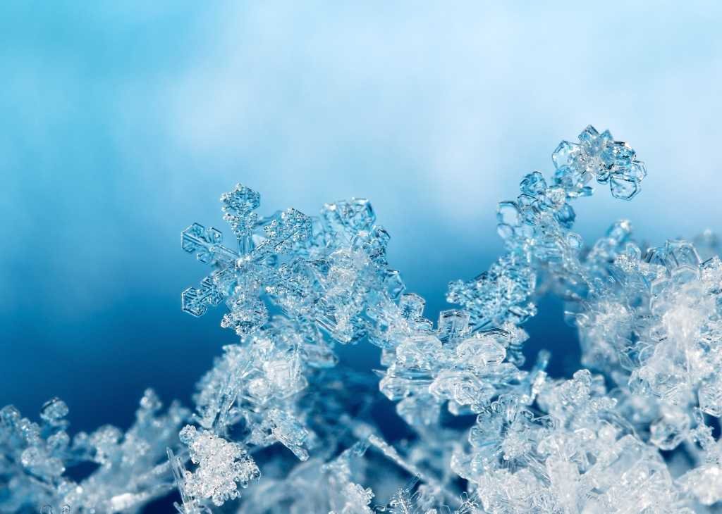 shutterstock 757358335 snowflakes on snow against clouds and blue sky